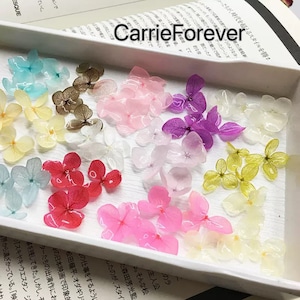 Peut inclure: Assortiment de fleurs d'hortensias pressées de différentes couleurs, dont le rose, le bleu, le violet, le blanc et le jaune. Les fleurs sont disposées dans une boîte blanche.