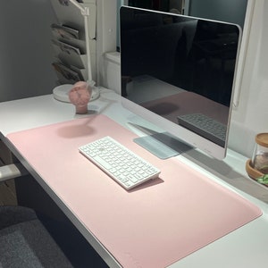 Schreibtischunterlage in der Farbe rosé. Die Größe ist 80 x 40 cm. Die Matte hat eine Korkunterlage. Sie ist ruschfest und wasserabweisend. Sie liegt auf einem Schreibtisch und eine Tastatur, Mauspad sowie weitere Utensilien finden darauf Platz.
