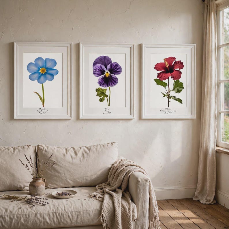 May include: Three framed botanical art prints hanging on a wall. The left print shows a blue Myosotis flower, the center print features a purple Viola flower, and the right print displays a red Hibiscus flower. Each print includes text below the flower.