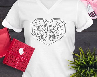 Puede incluir: Camiseta blanca de cuello en V con un dibujo de línea negra de dos cráneos formando una forma de corazón.