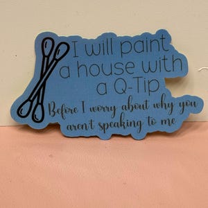 May include: Blue sticker with a white outline and a black illustration of two cotton swabs. The text on the sticker reads "I will paint a house with a Q-Tip Before I worry about why you aren't speaking to me."