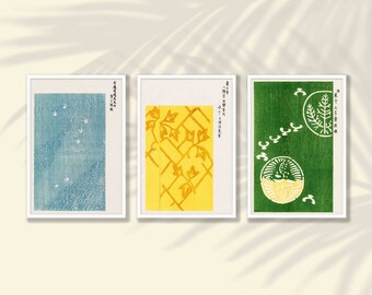 May include: Set of three framed art prints featuring Japanese-inspired designs. The prints showcase a blue abstract pattern, a yellow trellis with vines, and a green design with circular motifs. Each print has Japanese text.