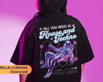 May include: An oversized black t-shirt featuring a graphic print on the back. The design includes an astronaut floating among planets with the text "ALL YOU NEED IS House and Techno" and additional small text details. The shirt is labeled BELLA+CANVAS.