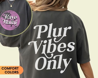 May include: A dark gray oversized t-shirt with the text "Plur Vibes Only" printed in white on the back. The front of the shirt features a pink disco ball with the text "Rave Mami" printed on it.