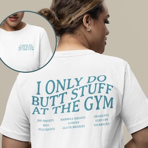 May include: White t-shirt with the text "I ONLY DO BUTT STUFF AT THE GYM" in teal. The shirt lists exercises like hip thrusts, barbell squats, and deadlifts. A smaller version of the text is on the front.