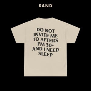 May include: A beige t-shirt with the text "DO NOT INVITE ME TO AFTERS I'M 30+ AND I NEED SLEEP" printed in black.