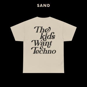 May include: A beige t-shirt with the text "The kids want Techno" printed in black on the back.