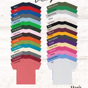 May include: A chart of 28 different t-shirt colors, with the names of each color listed below the corresponding color swatch. The text "Colors" is at the top of the chart. The text "*not all colors may be offered for this listing*" is at the bottom of the chart. The text "Han's Designs" is at the bottom right corner of the chart.