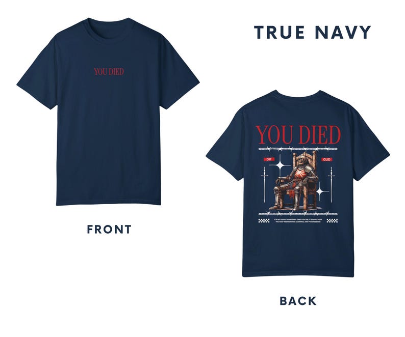 May include: A navy blue t-shirt with the text "YOU DIED" printed on the front in red. The back of the shirt features a graphic of a knight sitting on a throne with swords and the text "YOU DIED" printed in red.