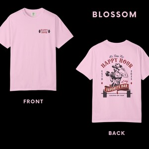 Op de afbeelding: Lichtroze t-shirt met een klein "HAPPY HOUR" barbell logo op de voorkant. De achterkant van het shirt heeft een afbeelding met de tekst "It's Time For HAPPY HOUR at my FAVORITE BAR" en een gewichtheffer ontwerp.