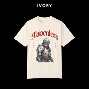 May include: A white t-shirt with a graphic of a knight in armor. The text "Maidenless" is printed in red above the knight.