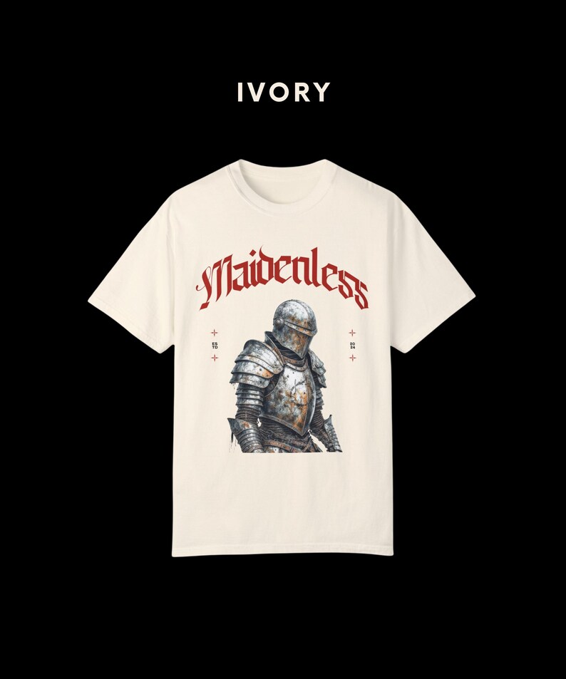 May include: A white t-shirt with a graphic of a knight in armor. The text "Maidenless" is printed in red above the knight.