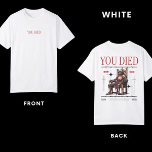 May include: White t-shirt with the text "YOU DIED" on the front and a graphic of a knight sitting on a throne with swords on the back.