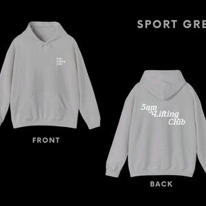 May include: A grey hooded sweatshirt with the text "5am Lifting Club" printed on the back. The front of the sweatshirt is plain.