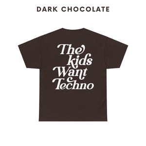 May include: Dark chocolate t-shirt with white text that reads "The kids want techno".