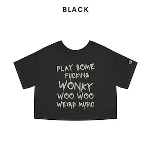 K&ouml;nnte beinhalten: Schwarzes, kurzes T-Shirt mit dem Text "PLAY SOME FUCKING WONKY WOO WOO WEIRD MUSIC" in einer verwaschenen Schriftart. Das Shirt hat kurze &Auml;rmel und ein Champion-Logo auf dem linken &Auml;rmel. Das Wort "BLACK" steht &uuml;ber dem Shirt.