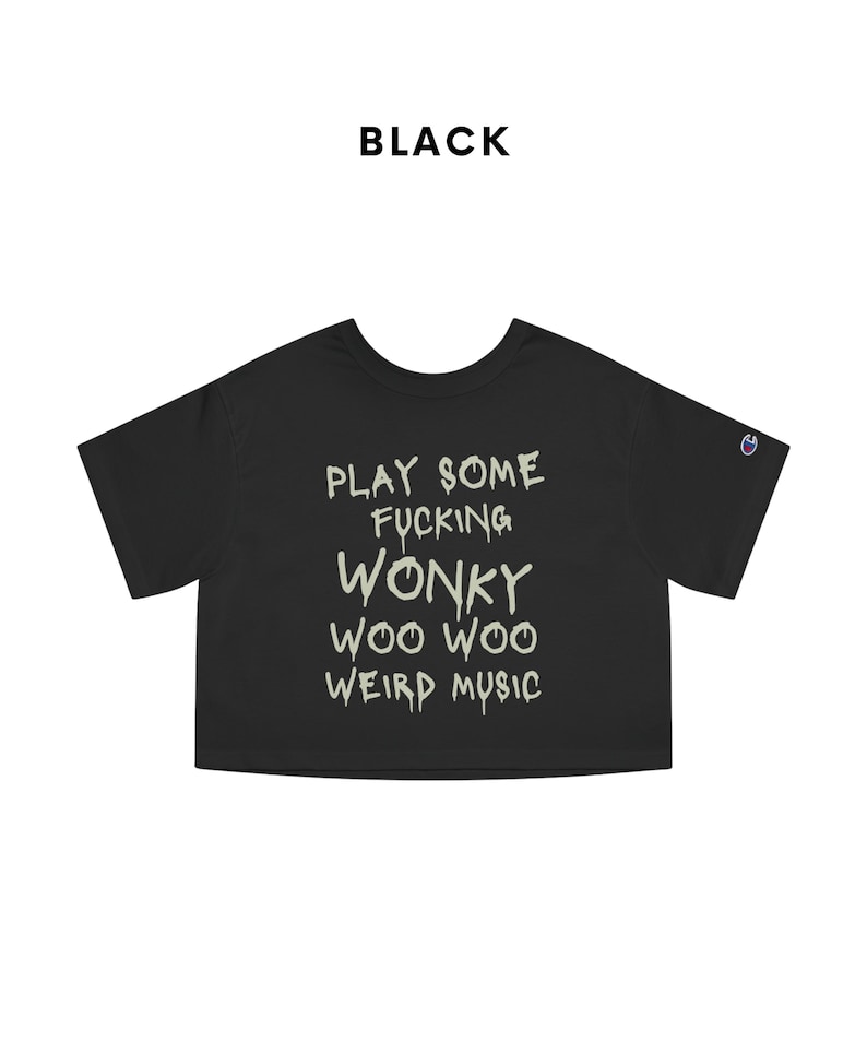 K&ouml;nnte beinhalten: Schwarzes, kurzes T-Shirt mit dem Text "PLAY SOME FUCKING WONKY WOO WOO WEIRD MUSIC" in einer verwaschenen Schriftart. Das Shirt hat kurze &Auml;rmel und ein Champion-Logo auf dem linken &Auml;rmel. Das Wort "BLACK" steht &uuml;ber dem Shirt.