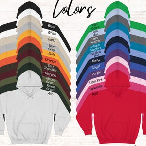 May include: A chart of hoodie colours with a sample hoodie in white and red. The colours include black, white, sand, sport grey, gold, orange, dark chocolate, maroon, military green, forest green, ash, Irish green, light blue, dark heather, antique sapphire, Carolina blue, navy, royal, purple, light pink, heliconia, and red. The text "Colors" is at the top of the chart. The text "*not all colours may be offered for this listing" is at the bottom of the chart. The text "Han's DESIGNS" is at the bottom right corner of the chart.