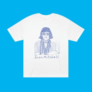 May include: White t-shirt with a blue line drawing of Joan Mitchell, a famous artist, wearing sunglasses and a scarf. The text "Joan Mitchell" is printed below the image.