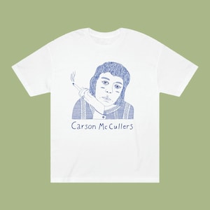 May include: White t-shirt featuring a blue line drawing of a person with short hair smoking a cigarette. The text "Carson McCullers" is printed below the drawing.