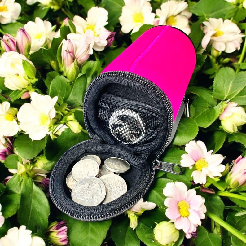 May include: A pink zippered pouch with a black zipper and a mesh pocket inside. The pouch is open and contains several silver coins.