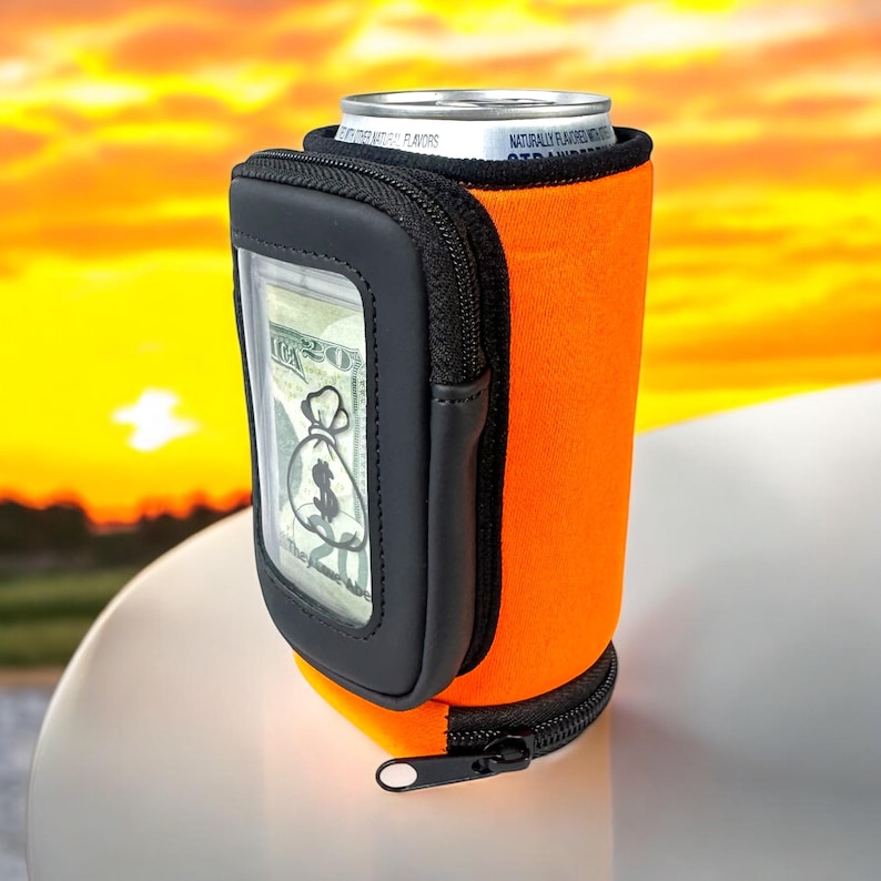 May include: Orange and black neoprene can cooler with a zippered pocket and a clear window for cash. The cooler is designed to hold a standard 12-ounce can.
