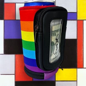 May include: A rainbow-colored neoprene can cooler with a black zippered pouch and a clear window for cash. The pouch has a zipper on the side and a zipper on the top.