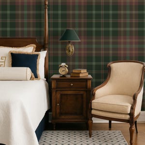 May include: A bedroom interior featuring dark green and brown plaid wallpaper, a wooden bed frame with white bedding, a dark blue accent pillow, a wooden nightstand with a brass alarm clock and books, a wall-mounted lamp, and a beige upholstered chair.