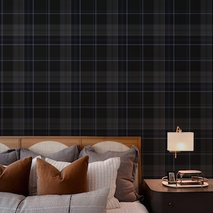 May include: A bedroom scene featuring a dark plaid wallpaper backdrop. The bed has a wooden headboard, a variety of pillows in shades of brown, gray, and white, and a bedside table with a lamp and decorative tray.