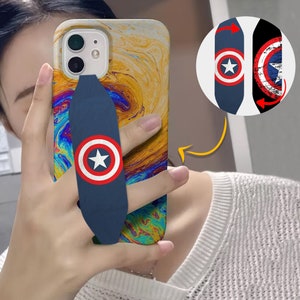 May include: A phone case with a colorful abstract design and a blue finger grip with a red, white, and blue Captain America logo. The grip is designed to be used with one finger to hold the phone.