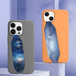 May include: Two phone cases with a galaxy print design. The cases are made of silicone and have a raised lip around the camera lens. The case on the left is gray and the case on the right is orange.