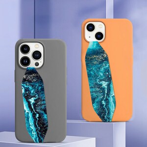 May include: Two phone cases with a blue and gold marbled design strap. The cases are gray and orange.