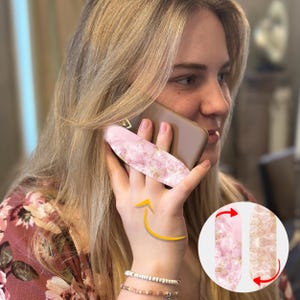 May include: Pink and gold marble phone grip with a gold accent. The grip is attached to a phone case and can be rotated 360 degrees.