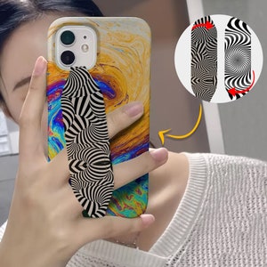 May include: A black and white swirl pattern phone grip attached to a yellow, blue, and green abstract phone case.