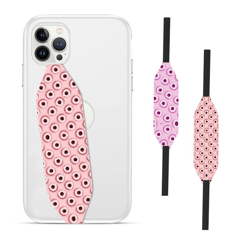 Switchbands reversible phone grip strap – Berry Donut design. Features a playful 3D pattern with a deliciously vibrant berry donut design, complete with colorful sprinkles. Provides a secure, comfortable grip for your phone while adding a sweet and fun touch to your device. The reversible design allows for easy style changes. Perfect for those who love whimsical, tasty-inspired designs and want to add a pop of personality to their phone.