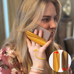 Może przedstawiać: Złote etui na telefon z falistym wzorem. Etui jest pokazane na telefonie trzymanym przy uchu osoby. Etui jest zaprojektowane tak, aby można je było obracać, aby zmienić wzór.