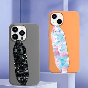 May include: Two phone cases with different geometric patterns. The case on the left is grey with a black and gold geometric pattern. The case on the right is orange with a pink, blue and white geometric pattern.