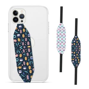 Switchbands reversible phone grip strap – Macaron design. Features a sweet 3D pattern inspired by pastel-colored macarons, with soft, delicate hues and charming details. Provides a secure, comfortable grip for your phone while adding a fun, elegant touch. The reversible design lets you switch up your style effortlessly. Perfect for those who love lighthearted, food-inspired designs and want a touch of whimsy on their phone.