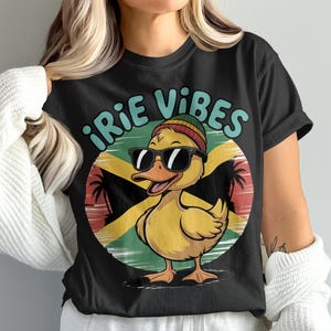 May include: Black t-shirt featuring a cartoon duck wearing sunglasses and a beanie, with the text "iRIE VIBES" above a Jamaican flag design. The duck is yellow with an orange beak.