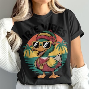 May include: Black t-shirt featuring a cartoon duck wearing sunglasses, a beanie, and a gold chain. The duck is set against a sunset backdrop with palm trees and the words "IRIE VIBES" in a bold font.