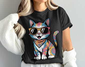 May include: Black t-shirt featuring a colorful cartoon cat wearing sunglasses. The cat has a patterned design in shades of blue, pink, yellow, and orange. The cat is sitting with its tail curled and a patterned bandana.