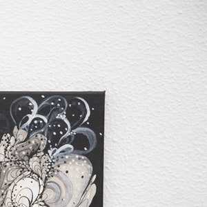 Pode incluir: Pintura abstrata em uma tela preta com redemoinhos e pontos brancos e cinzentos.