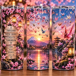 May include: A cylindrical metal tumbler featuring a vibrant landscape with cherry blossoms, a mountain, a pagoda, and paper cranes. A wooden sign displays the text: A THOUSAND PAPER CRANES A BRIGHTER TOMORROW HOPE HEALS KINDNESS LIVES ON.