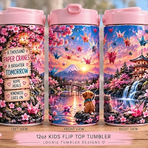 May include: A 12oz kids flip top tumbler featuring a wrap-around design of a Japanese landscape with cherry blossoms, paper cranes, a mountain, a pagoda, a waterfall, and a puppy. The text reads A THOUSAND PAPER CRANES A BRIGHTER TOMORROW HOPE HEALS KINDNESS LIVES ON.