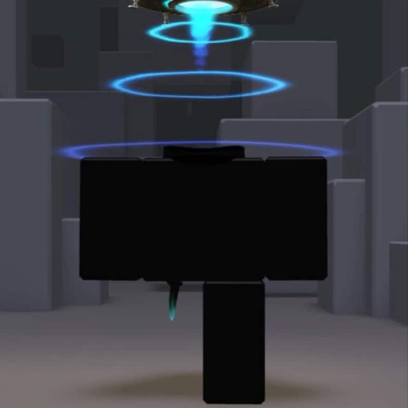 Puede incluir: Una figura digital negra y de forma c&uacute;bica se encuentra en un entorno gris. Sobre la figura, un objeto circular emite una luz azul brillante que proyecta tres anillos azules conc&eacute;ntricos y luminosos hacia la cabeza y los hombros.