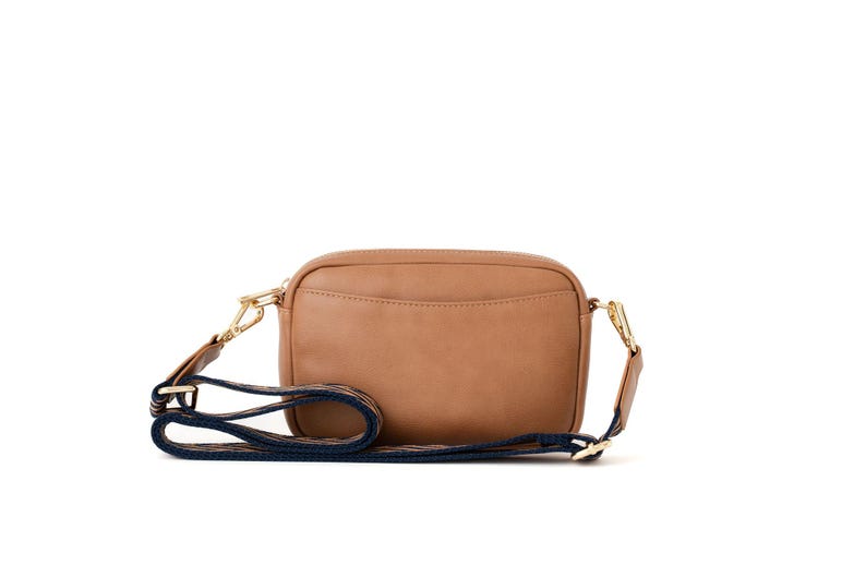 May include: A brown leather crossbody bag with a navy blue and white striped strap.