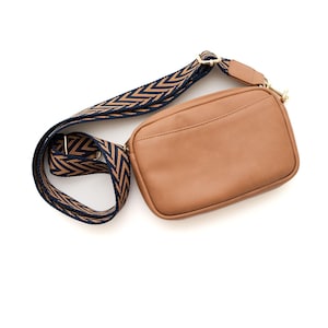 May include: A brown leather crossbody bag with a black and brown chevron patterned strap.