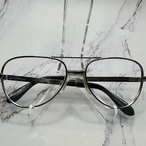 May include: Silver aviator style eyeglasses with a black nose bridge and black earpieces.