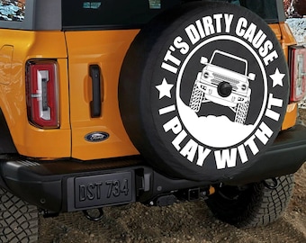 May include: A black spare tire cover with white text that reads "It's Dirty Cause I Play With It" and a white silhouette of a Ford Bronco. The tire cover has a white star on either side of the text.