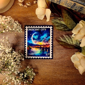 K&ouml;nnte beinhalten: Eine blaue und wei&szlig;e Briefmarke mit einer Aquarell-Illustration eines Halbmondes &uuml;ber einer Stadtlandschaft bei Nacht. Die Marke tr&auml;gt die Aufschrift "Crescent City" und "10&cent;".